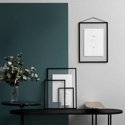 4 schwarze Rahmen mit Tisch und farbiger Wand
